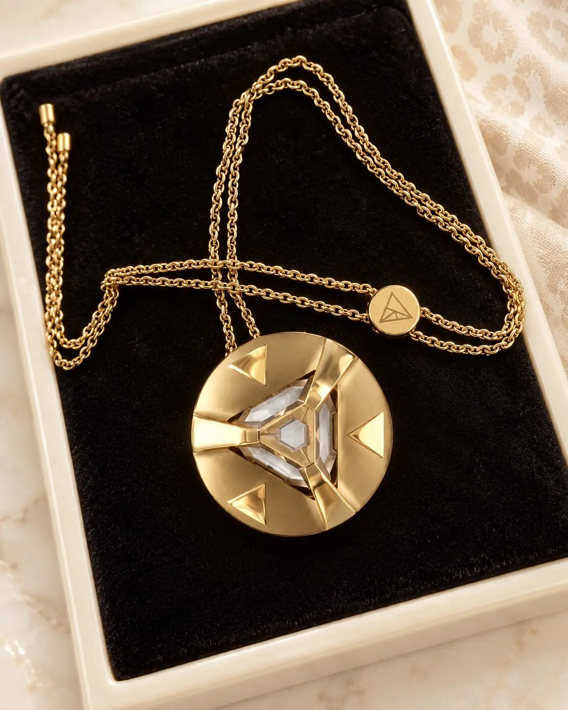 Gold ARQ pendant resting in its black presentation box