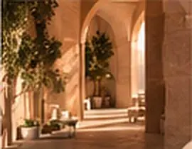 A warm stone arcade with olive trees, lit at golden hour
