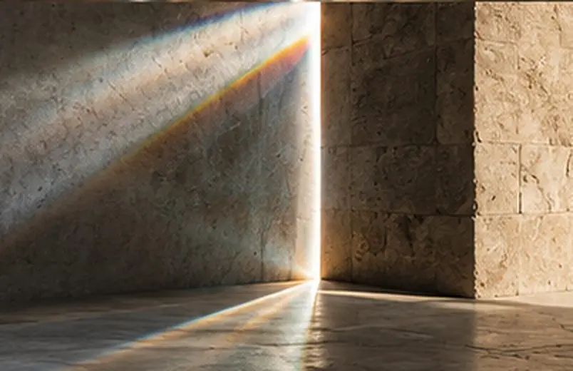 A blade of light and a small rainbow on a stone wall